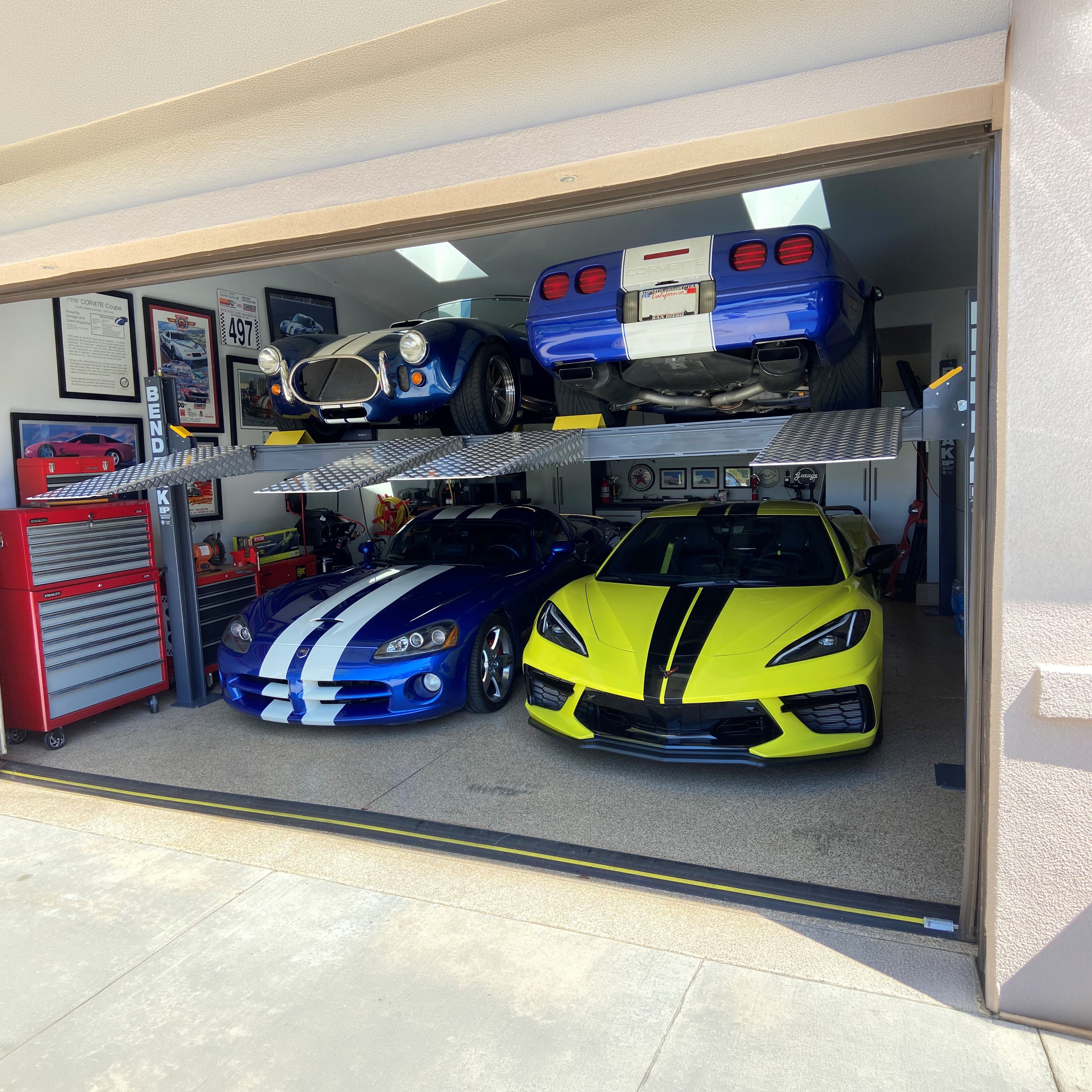 BendPak HD-9SWX dual-platform lift supporting vehicles in a residential garage.