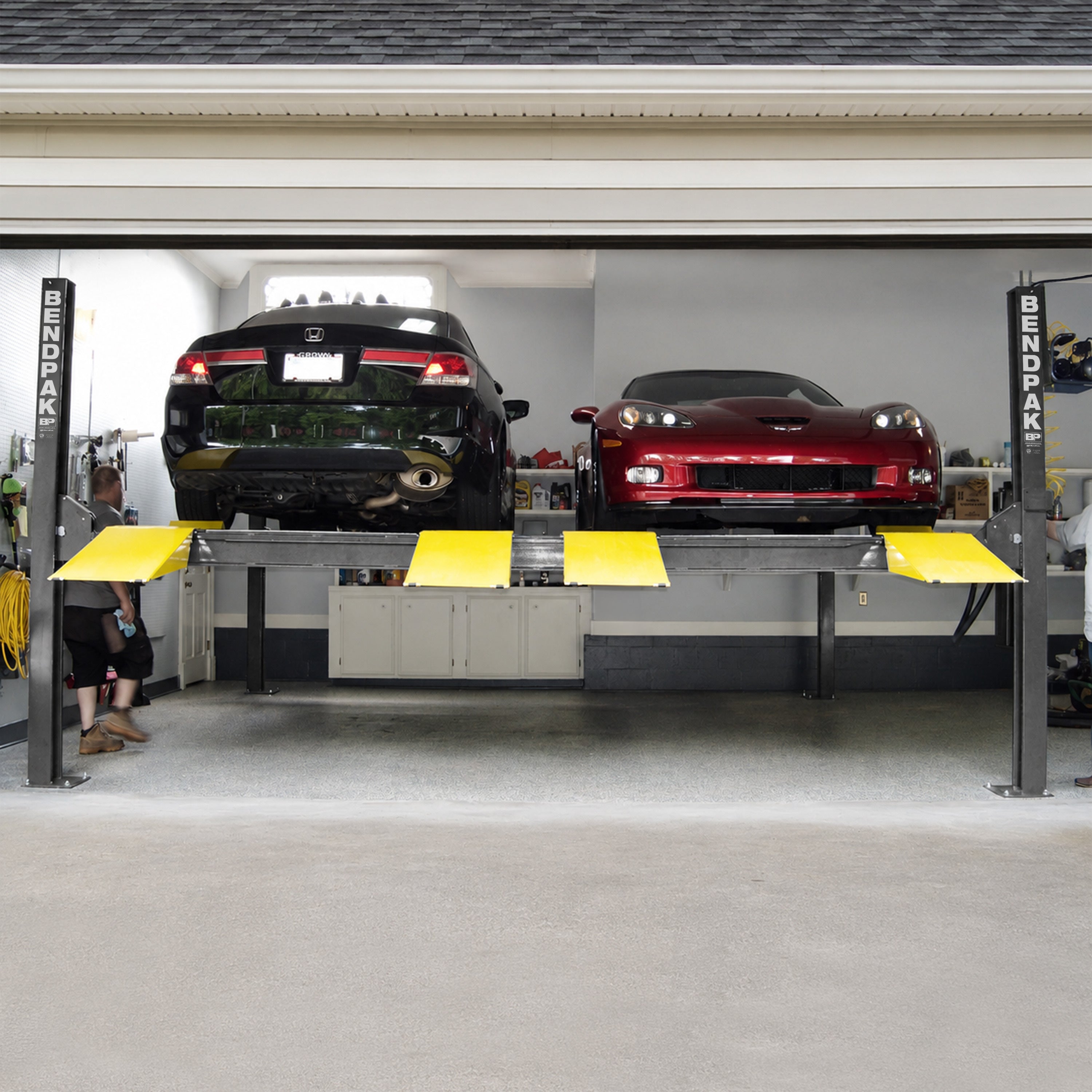 BendPak HD-9SW-E tandem four-post lift raising sports cars in a home garage storage setup.