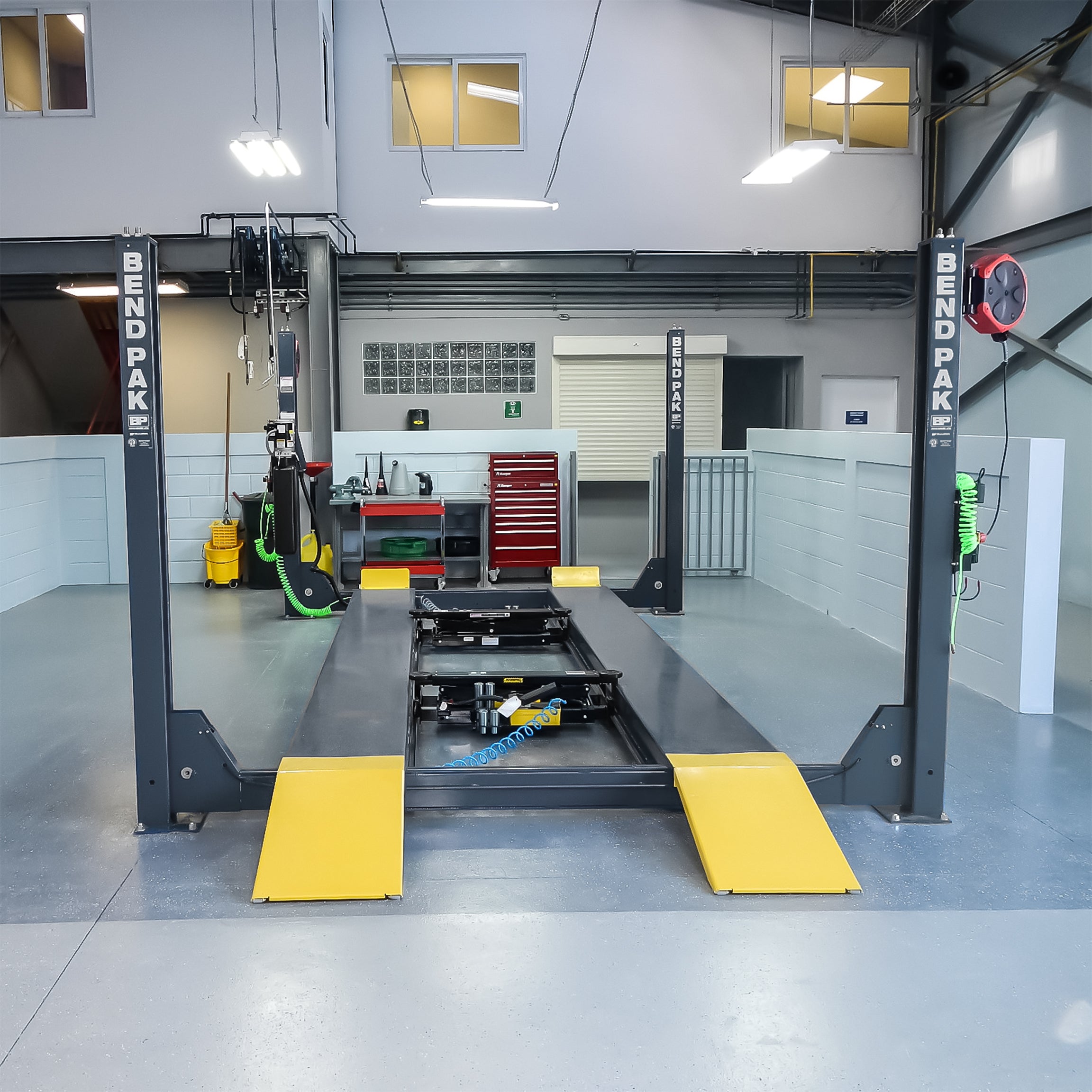 BendPak HDS-14 four-post lift in an industrial mechanic shop service bay.
