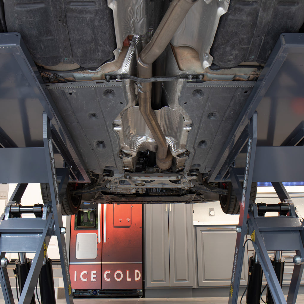 Vehicle undercarriage accessible through the open-center design of a BendPak MDS-6LP mid-rise scissor lift in a garage.