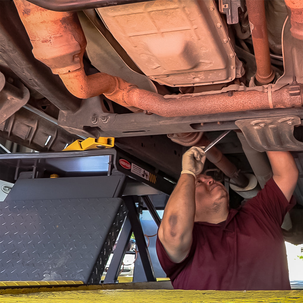 BendPak P-9000LT low-rise lift with integrated safety locks while a technician works underneath.