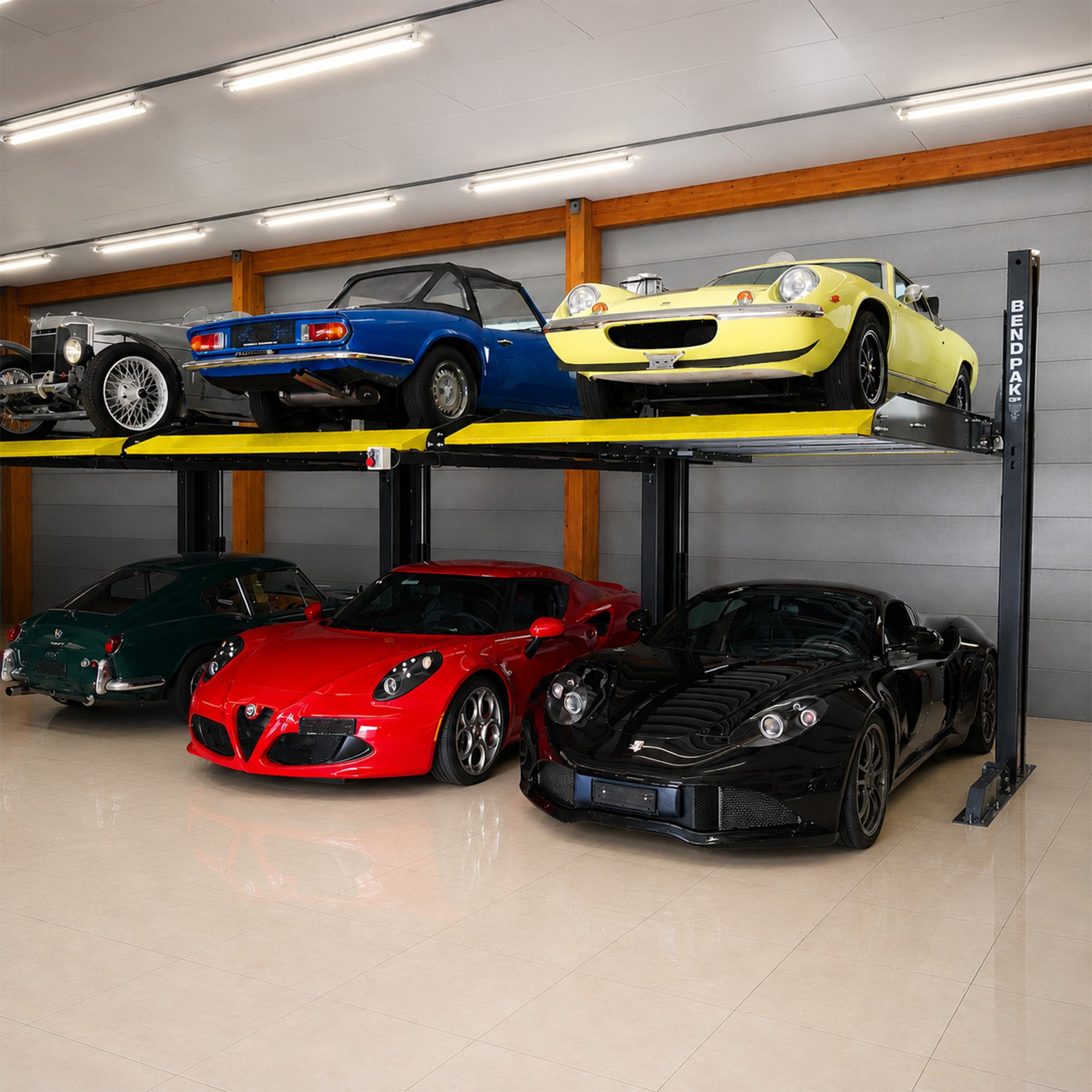 Collector cars stacked on a BendPak PL-6000DC two-post parking lift in a private garage.