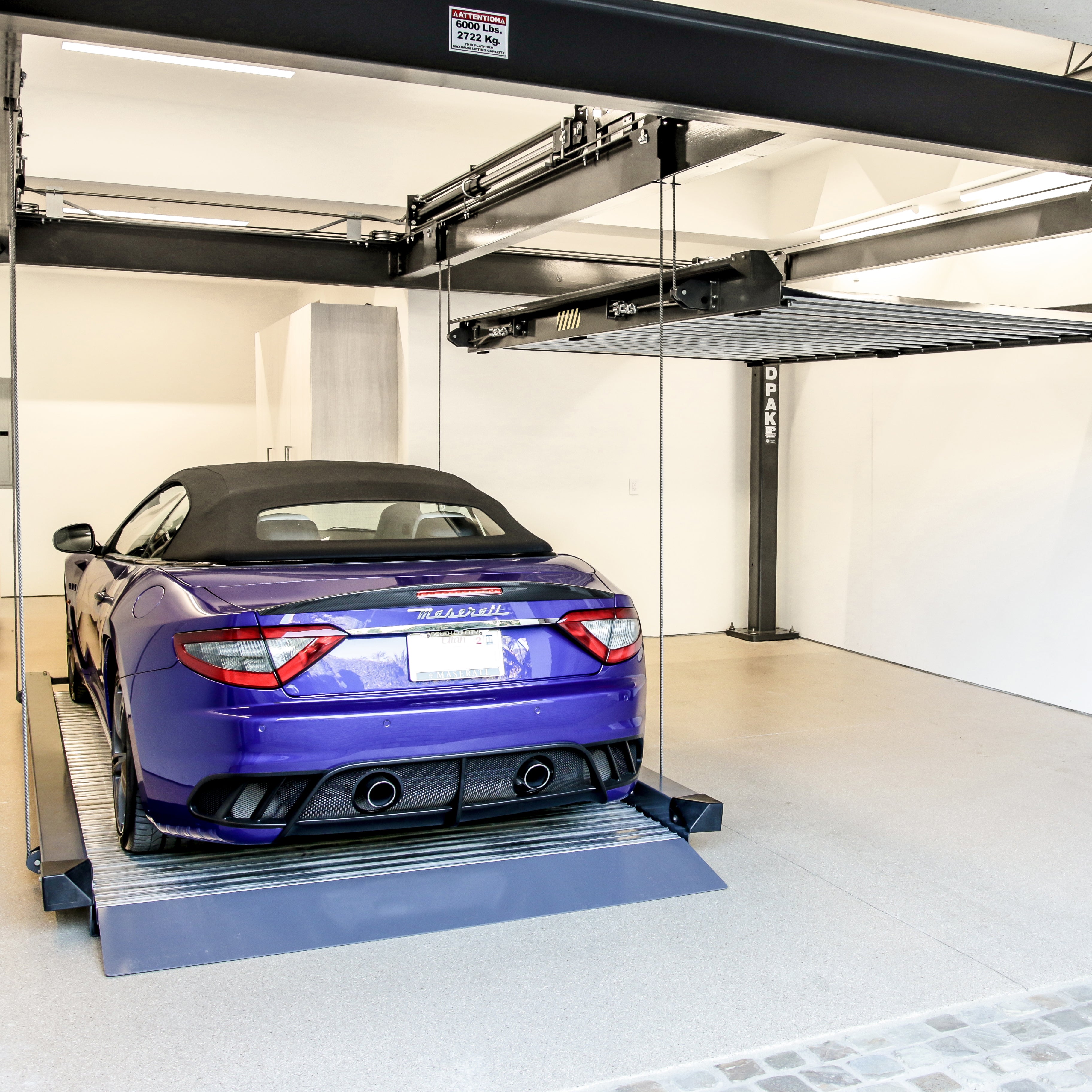 BendPak PL-6KT triple independent platform parking lift storing luxury vehicles.