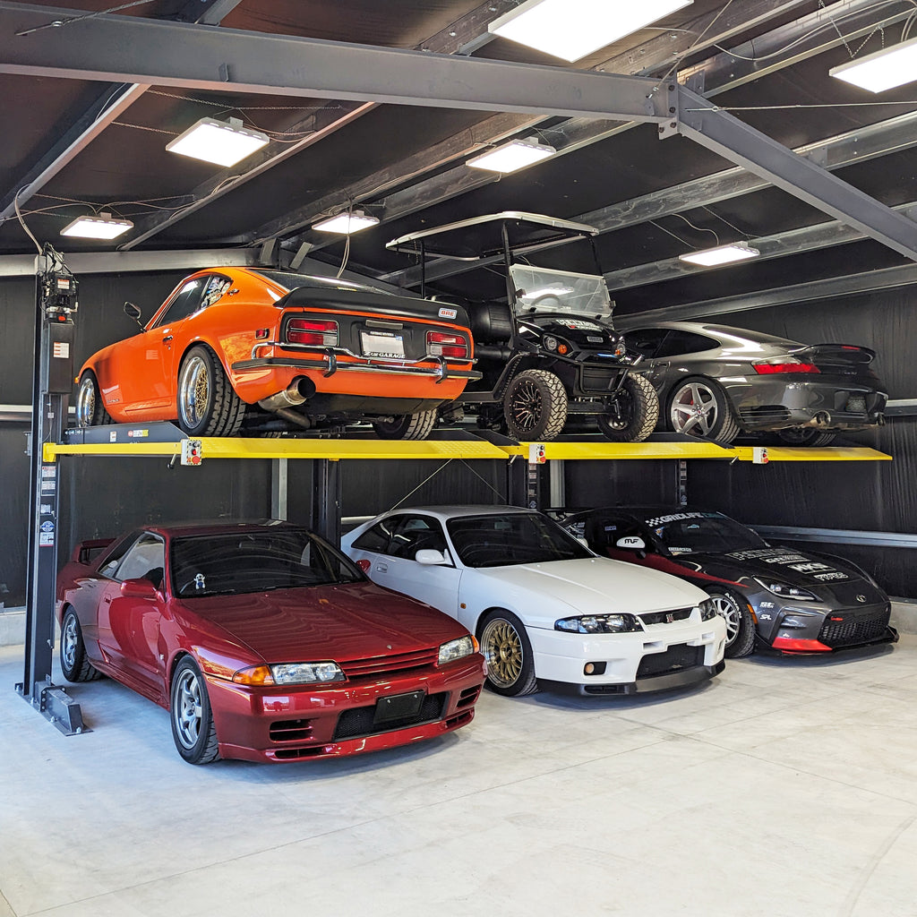 BendPak PL6000DC shared-column two-post parking lifts storing a car collection.