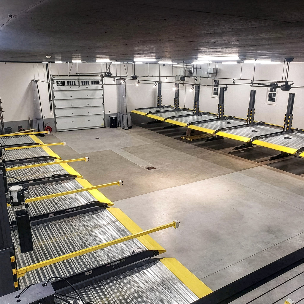 BendPak PL6000DCX daisy-chained shared-column parking lifts with low-profile approach ramps.