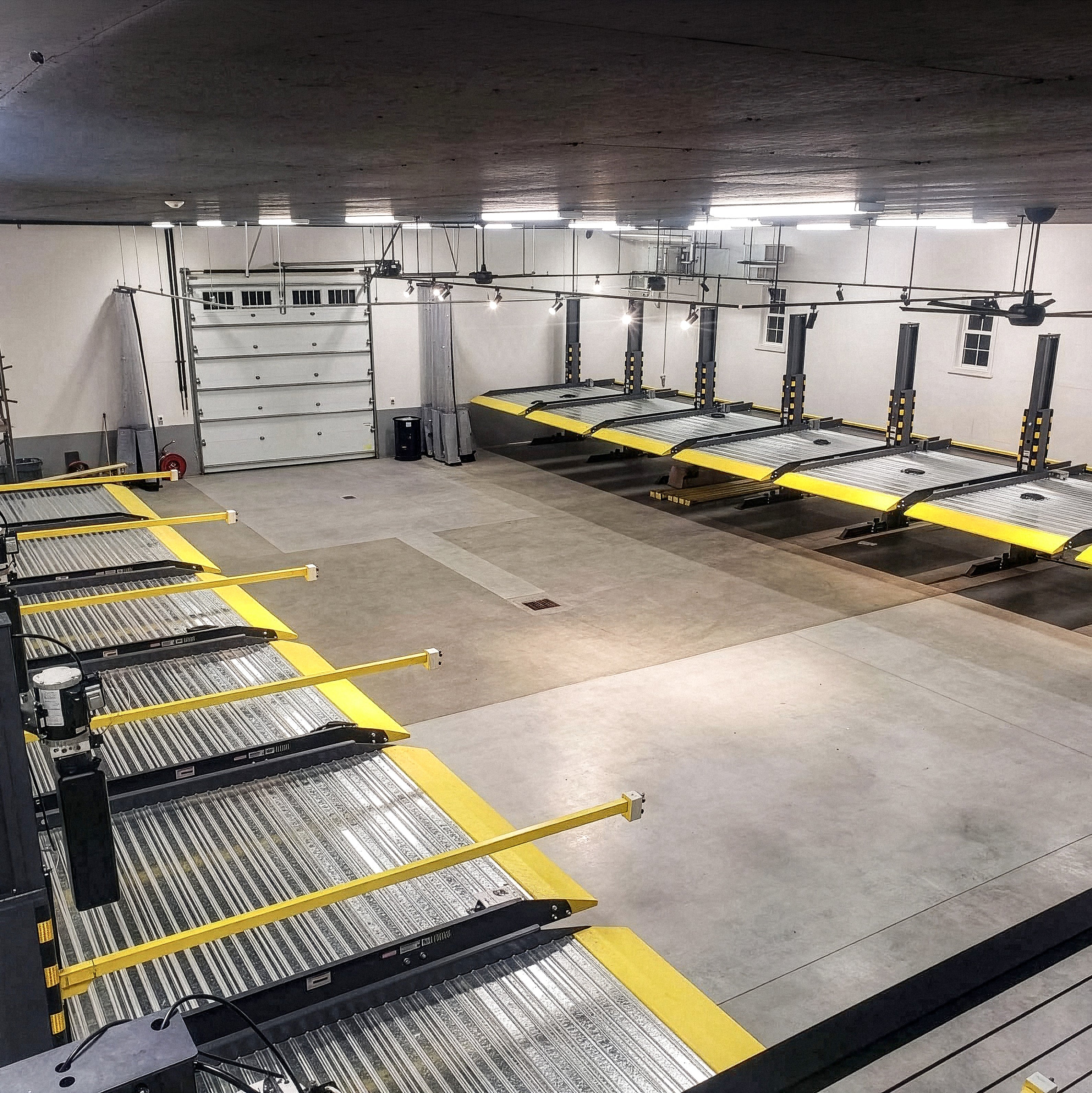 BendPak PL6000DCX daisy-chained shared-column parking lifts with low-profile approach ramps.