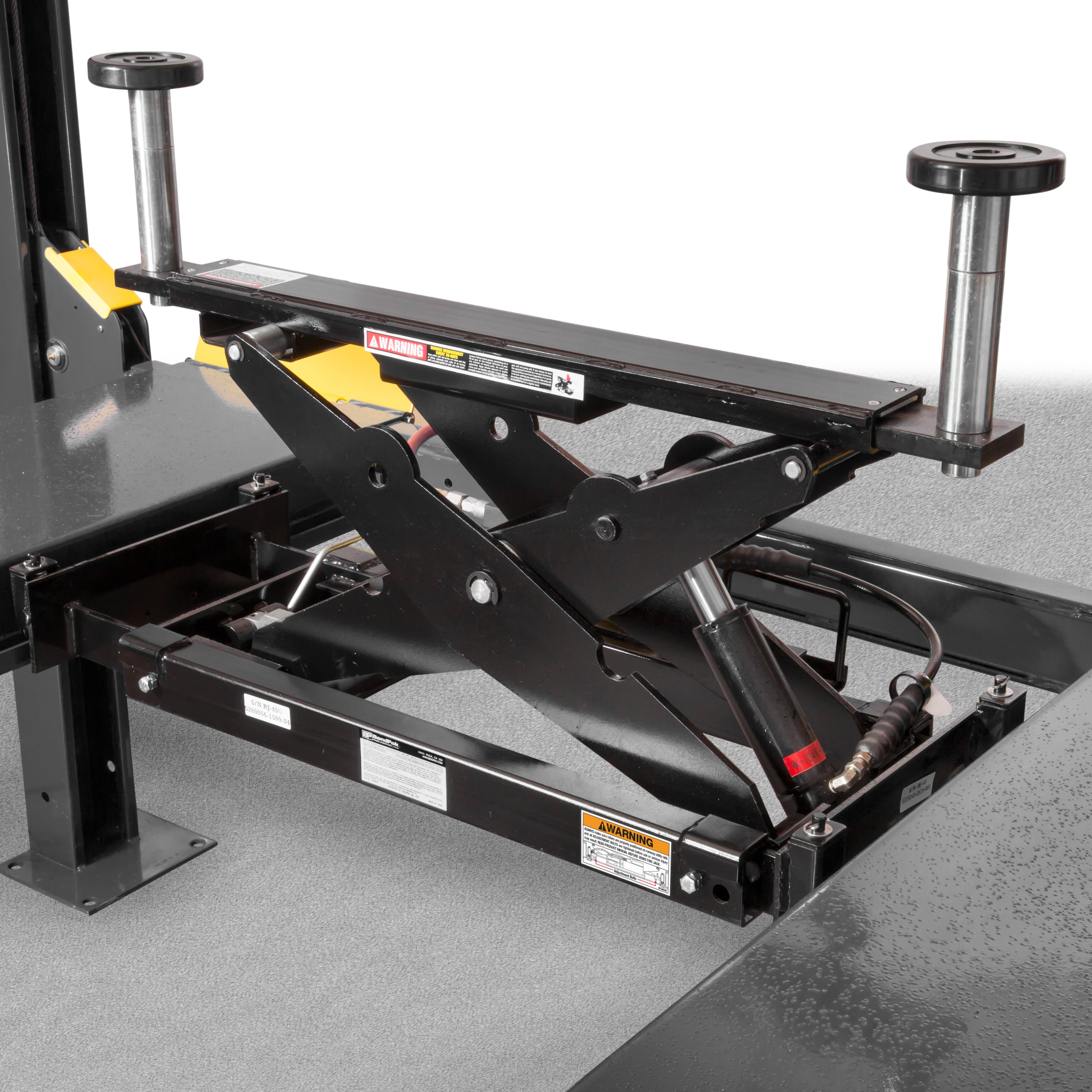 BendPak RJ45LP low-profile rolling bridge jack mounted between four-post lift runways.
